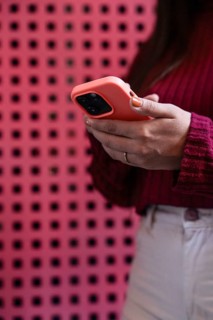 Closeup of anonymous woman in a red sweater holds a smartphone with a pink case, standing in front