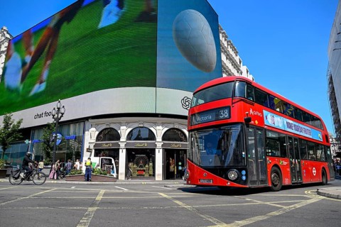 Red double-decker bus in front of digital billboards at Piccadilly Circus, City of Westminster,