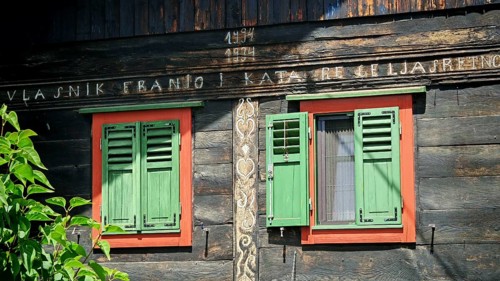 Old traditional wooden house with green shutters and antique lettering, rustic and historic