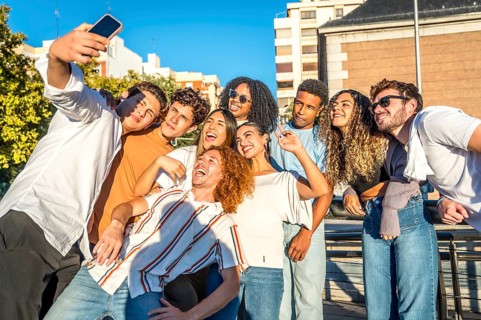 Smiling diverse young friends enjoying a day at city taking selfie together
