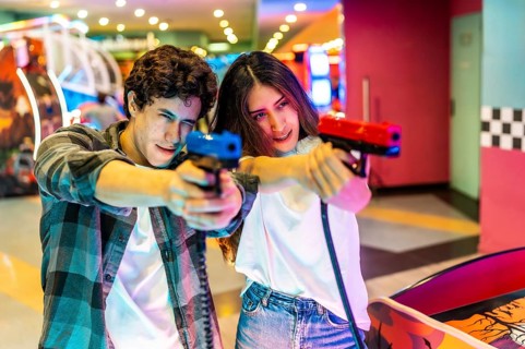 Young man and woman enjoying a fun day at the amusement park, playing a shooting game together