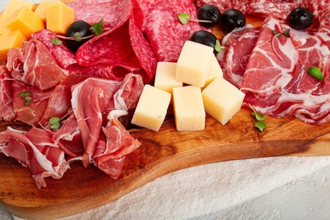 Assorted, sliced meat appetizer, prosciutto, salami and ham, with cheese and olives, on a wooden