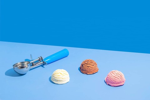 Three scoops of ice cream in chocolate, strawberry, and vanilla on a vibrant light blue and blue