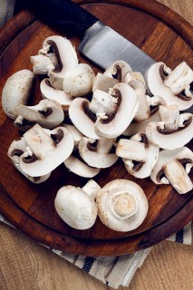 Fresh mushrooms, chopped, in a wooden bowl, whole, top view, no people