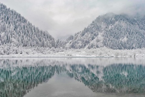 Mountain lake in winter. Snow-covered mountains are reflected in the water. Winter landscape, A