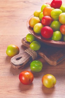 Cherry plum tkemali, fruit, plum variety, in a wooden plate, Georgian cuisine, top view, no people