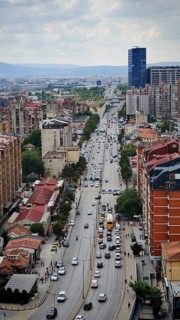 Main street in a city seen from above with heavy traffic and surrounding buildings, Pristina,