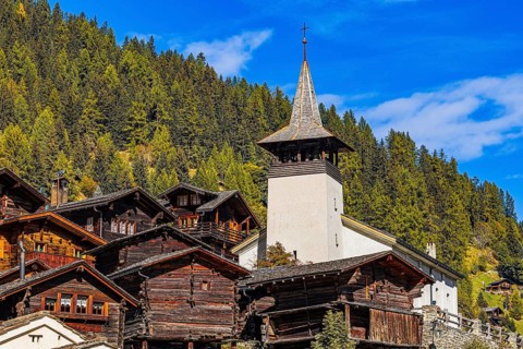 Old wooden houses and the Saint Theodule church in the historic village centre, Grimentz, Val