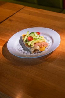 An upscale starter with salmon, avocado and tomatoes served decoratively on a plate, Café Kuh,