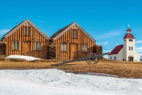 Cottages, old agricultural machine, church behind, snowy farm Mödrudalur, winter, highlands between
