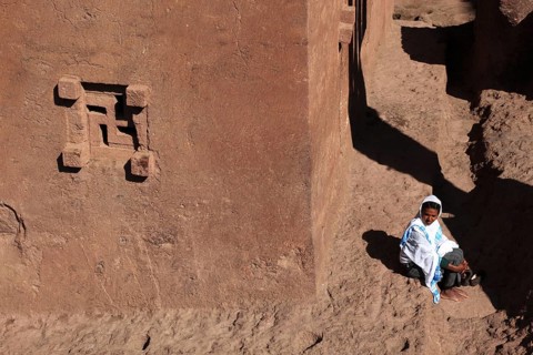 Rock churches of Lalibela, woman, pilgrim sitting in front of the Bete Golgata, Golgotha Church,