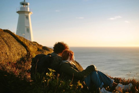 A couple watches a stunning sunset near the Cape Spear Lighthouse in Newfoundland and Labrador,