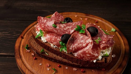 Sandwich, grain bread, with cream cheese and salami, black olives, micro-greens, top view,