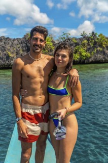 Young couple standing on boat with snorkeling gear, enjoying breathtaking view of turquoise water
