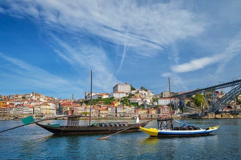 View of Porto rabelo boats on Douro River by Ribeira, Portugal, with moored traditional boats, wine