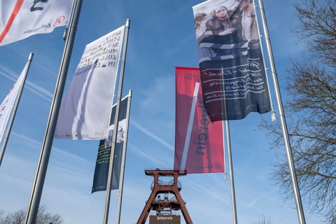 Double trestle headframe, flags in front of it, Shaft XII, Zollverein Coal Mine Industrial Complex,