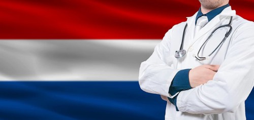 Netherlands healthcare concept. Male doctor on Dutch flag. Doctor with crossed arms on Dutch flag