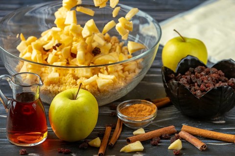 Apple pieces fall into the bowl full of ingredients for apple strudel