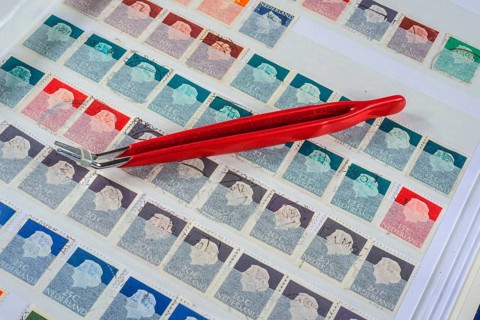 Philately, tweezers on album page with Dutch stamps