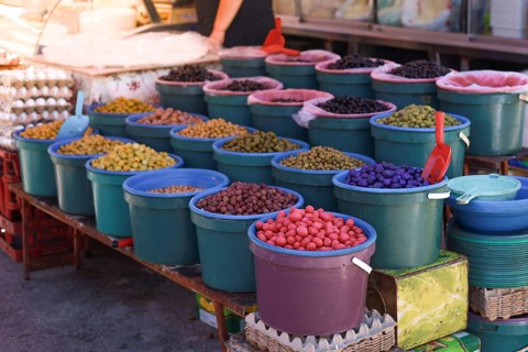Various colorful olives displayed in buckets at a market stall