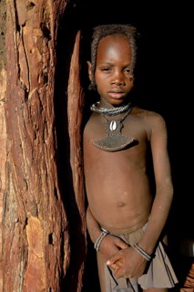 Himba girl standing at the door of her hut, Omohanja, Kaokoland, Kunene, Namibia