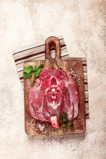 Raw steak, veal neck on the bone, fresh meat, on a cutting board, with spices, top view, without