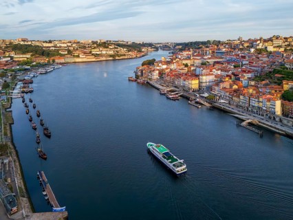 Drone view of Douro River in Porto, Portugal, with a tourist boat between Ribeira and Vila Nova de