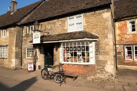Old bicycle outside the village bakery shop, Lacock, Wiltshire, England, UK