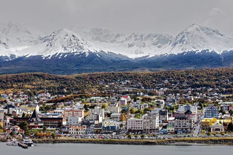 Picturesque view of the city of Ushuaia on the shore with snow-capped mountains in the background