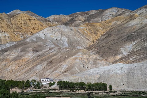 Traditional house and cultivated fields in front of mountain landscape, erosion landscape near Lo