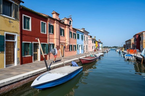 Young man in front of colourful houses on the canal, canal with boats and colourful house facades,