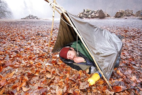 Nature photographer in a makeshift night camp on autumn leaves in spring, bad weather, Saxon