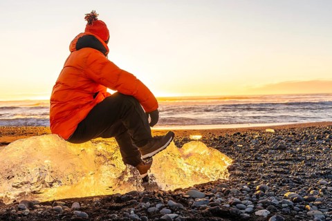 Sitting on a giant chunk of ice at sunrise on Diamond Beach Iceland in winter