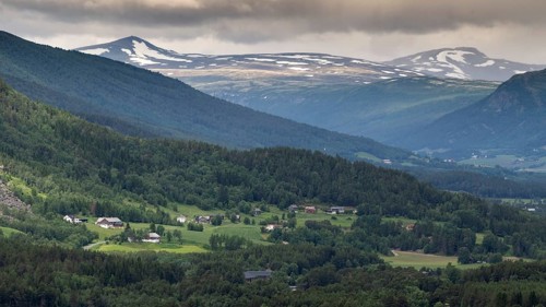 Landscape with houses, farms, mountains, forests and scattered villages under a cloudy sky,