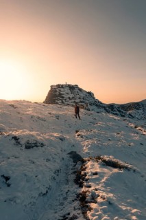 A lone hiker traverses the snow-covered terrains of Siete Picos, Guadarrama Mountains, Madrid. The