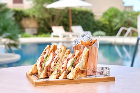 A mouthwatering platter of ham, cheese, and tomato sandwich served with crispy fries in a basket.