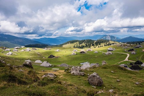 A wide panoramic view of a traditional shepherd village with unique wooden huts scattered across