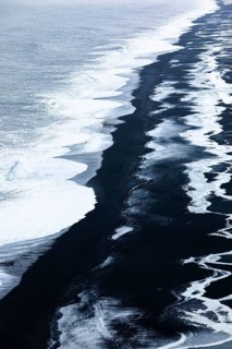 Foamy white waves and icy surfaces on the black pebble beach Skogarsandur, near Dyrholaey,