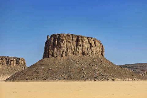 A monumental rock in the middle of an arid desert landscape, Lonely mountain created by erosion in