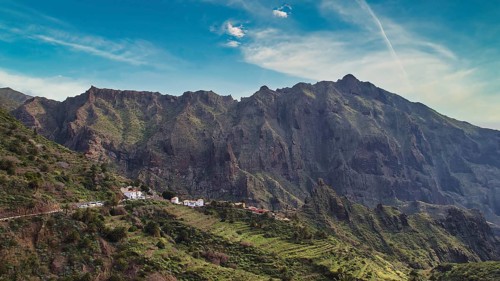Impressive mountain range with green vegetation and small village in the foreground, Masca,
