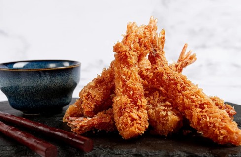 Shrimp in tempura, deep fried, on black slate, with sauce, light marble table, no people