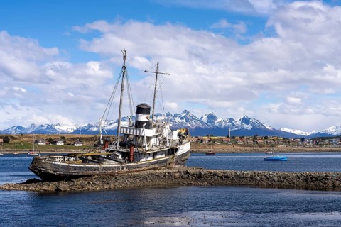 Shipwreck of the Saint Christopher steam tug stranded on rocks in the harbor, behind small