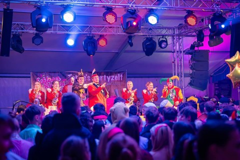 Carnival atmosphere with people in costumes on stage, illuminated in bright colours, carnival,