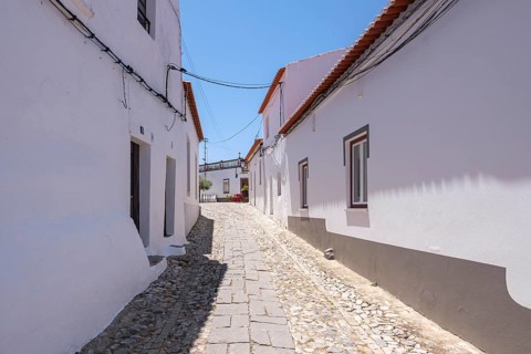 Narrow alley with white buildings and cobblestones in sunny weather, Serpa, Beja, Portugal