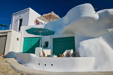 Modern white house with green doors and seating area under parasol, Syrmata, boat garages,