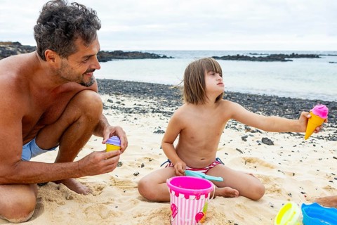 A young girl with Down syndrome enjoys playful moments with her family on the beach, playing with