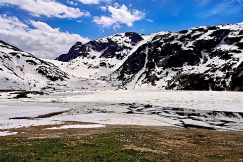 Ice floes drift in the half-frozen upper Murgsee, in the foreground, white flowering spring