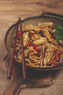 Udon noodles, with squid and vegetables, on a wooden table, homemade, no people