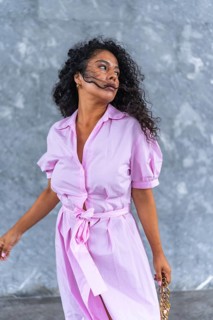 Vertical portrait of a stylish and elegant latin woman with pink clothes posing looking away