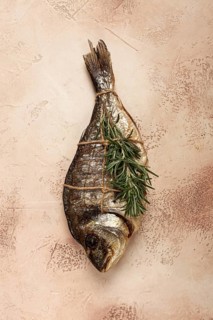 Hot smoked dorado fish, with a sprig of rosemary, tied with a rope, on the table, top view, smoked
